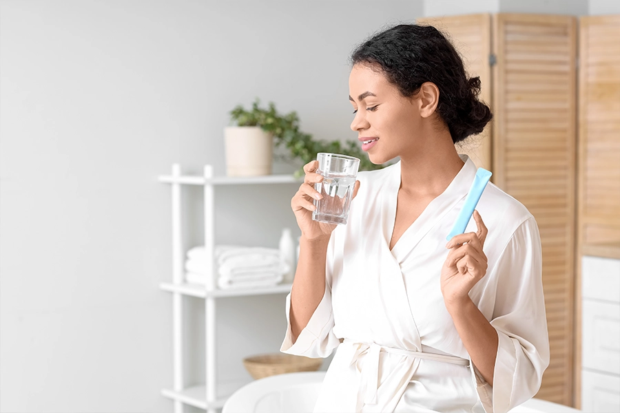 Woman taking collagen powder in bathroom 